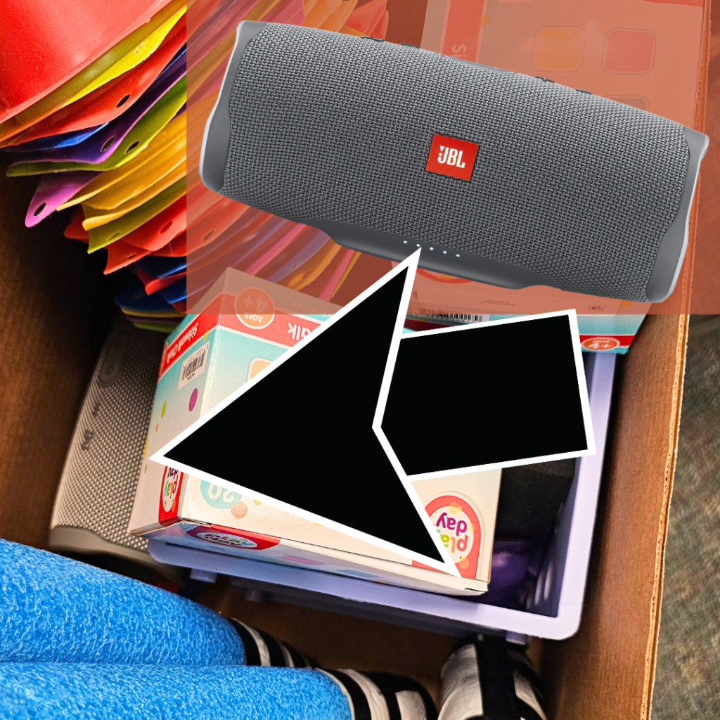 A box full of cones, chalk , and a bluetooth speaker.  A large arrow points to the hidden speaker. 